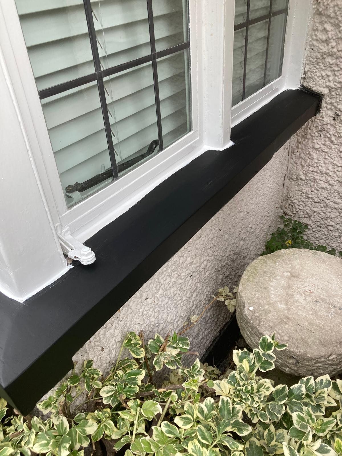 Window sill finished in black gloss beneath white window frames